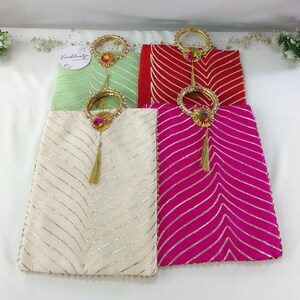 May include: Four decorative fabric bags with gold handles and tassels. The bags are in green, red, white, and pink with a gold and white striped pattern.
