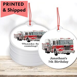 May include: Round white favor tags with a red fire truck image. One tag says "Thanks for coming!" and the other says "Jonathan's 7th Birthday".