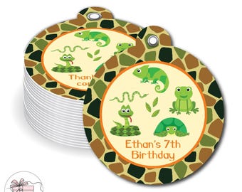 May include: A stack of round paper gift tags featuring a brown, green, and black camouflage border. The center displays cartoon illustrations of a chameleon, snake, frog, and turtle with the text Ethan's 7th Birthday in orange.