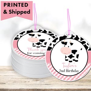 May include: Round pink and black favor tags with a cartoon cow and the text "Thank you for coming" and "Taylor's 2nd Birthday".