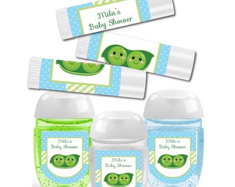 May include: Set of four baby shower favors featuring peapod designs. Two green and blue hand sanitizers with labels that read "Mila's Baby Shower" and two lip balms with the same label.