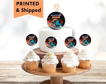 Puede incluir: Un pastel blanco con una vela encendida en la parte superior. La vela tiene un adorno redondo con un gráfico de patines y el texto "Happy Birthday Andrew". Hay cinco cupcakes con el mismo adorno en un soporte para pasteles de madera.