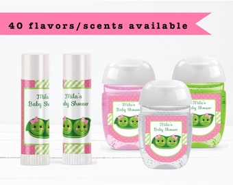 May include: Four favor bottles with labels that say "Mila's Baby Shower" and feature a peapod with two peas with faces. The bottles are clear, pink, and green.