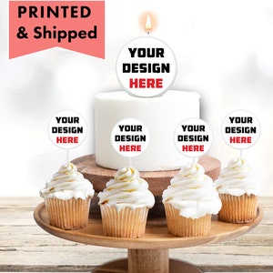 May include: A white cake with white frosting and a round, white cake topper with the text "YOUR DESIGN HERE" in black. There are five cupcakes with white frosting and round, white toppers with the text "YOUR DESIGN HERE" in black.
