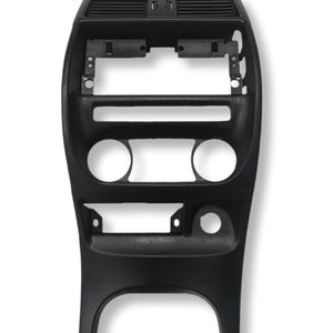 以下が含まれることがあります： 黒い車のダッシュボードセンターコンソールの交換品。プラスチック製のコンソールには、ラジオ、通気口、その他のコントロール用の開口部があります。さまざまな取り付けポイントと円形の切り欠きを備えた曲線的なデザインが特徴です。