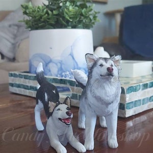 May include: Two realistic dog figurines, one black and white and one gray and white, standing on a wooden surface. The figurines are detailed and lifelike.