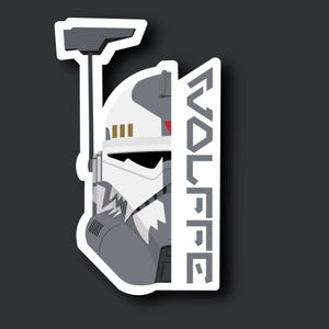 May include: A white and grey helmet with a red stripe and the word "WOLFFE" printed on the side. The helmet has a black visor and a grey antenna.