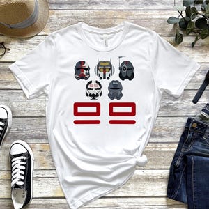 Puede incluir: Camiseta blanca con un gráfico de cinco personajes de dibujos animados con cascos y el número 99 en rojo. Los personajes son del universo de Star Wars.