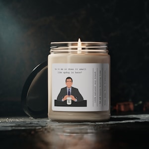 Puede incluir: Una vela beige con una etiqueta en blanco y negro que presenta una ilustración de dibujos animados de un hombre con traje sosteniendo una taza que dice "World's Best Boss". La etiqueta también incluye el texto "Is it me or does it smell like updog in here?" y "100% natural soy blend, 50-60 hours burning time, Keep away from flammables."
