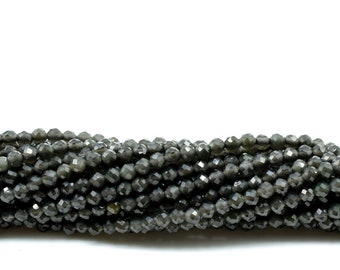 May include: A strand of dark gray faceted gemstone beads. The beads are small and round, with a shiny, metallic finish.