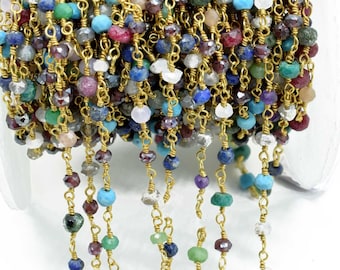 May include: A gold chain with a variety of gemstone beads, including turquoise, lapis lazuli, ruby, and emerald. The chain is strung with small, faceted beads.