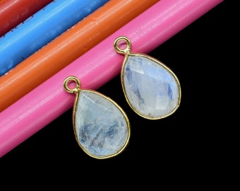 May include: Two teardrop-shaped moonstone pendants with gold-tone settings. The stones are a light blue color with a shimmery finish.