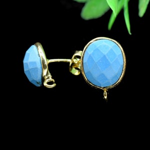 May include: A pair of gold earrings with light blue oval-shaped stones. The stones have a faceted texture.