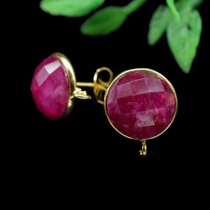 Puede incluir: Un par de pendientes de oro con piedras redondas de rubí rojo facetadas.