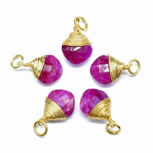May include: Five pink gemstone pendants wrapped in gold wire. Each pendant has a gold loop for attaching to a chain or cord.