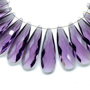 May include: A strand of purple faceted teardrop beads, strung on a silver wire.