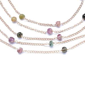 Puede incluir: Collar de múltiples cadenas con una cadena de oro y cuentas de piedras preciosas de colores. Las cuentas son una mezcla de rosa, verde y negro.