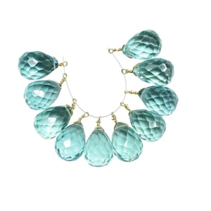 Può includere: Una fila di perline di pietra preziosa di forma a goccia di colore blu chiaro con anelli di salto dorati.