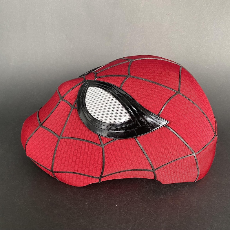 May include: A red Spider-Man mask with a textured pattern and black webbing. The mask features large white eye lenses with a black border. The overall design is a replica of the superhero's iconic head covering.