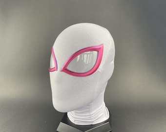 Puede incluir: Una máscara de tela blanca con formas de ojos delineadas en rosa e inserciones de malla. La máscara está diseñada para cubrir la cabeza y el cuello, y se muestra sobre un soporte negro sobre un fondo gris. La máscara es probablemente para cosplay o disfraces.