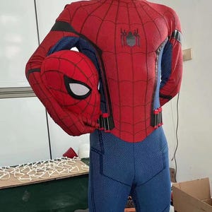 May include: A red and blue Spider-Man costume with a matching mask. The costume features a webbed design on the red areas and a spider emblem on the back. The blue areas have a textured pattern.