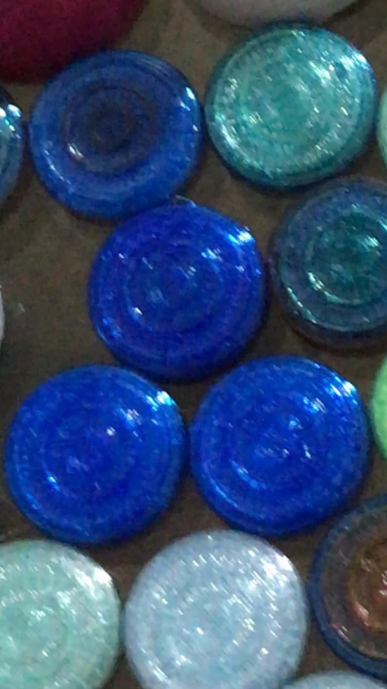 May include: A collection of round, iridescent glass tiles in shades of blue, green, and white. The tiles have a textured surface and a slightly raised centre.