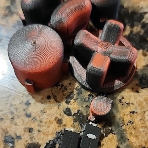 May include: A set of red and black gaming buttons with a black and red star-shaped button. The buttons are made of a textured plastic and have a worn look. Two black switches are also included.