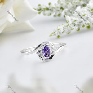 Peut inclure: Une bague en argent avec une pierre ovale violette et de plus petites pierres claires serties dans une bande torsadée.