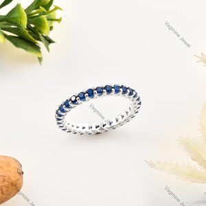 Peut inclure: Une bague en argent avec une rangée de petites pierres bleues rondes.