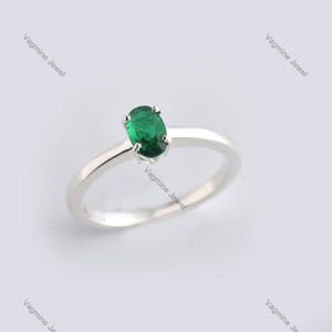 May include: A silver ring with a green oval gemstone.