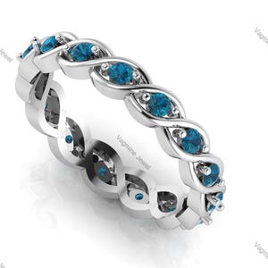 Peut inclure: Une bague en argent avec un design torsadé et des pierres bleues. La bague est sertie de plusieurs petites pierres bleues rondes.
