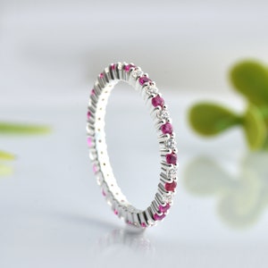 Peut inclure: Une bague éternité en argent avec une rangée de pierres de rubis et de diamants alternées.