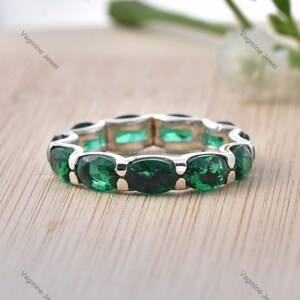Op de afbeelding: Een zilveren ring met een rij ovale groene edelstenen.