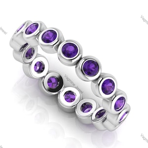 May include: A silver band ring with a row of bezel-set amethyst gemstones. The ring is made of white metal and has a polished finish.