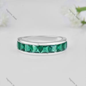 Peut inclure: Une bague en argent avec une rangée de pierres précieuses carrées de couleur vert émeraude.