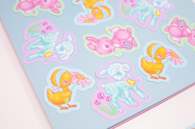 May include: A set of colorful Easter stickers featuring cute cartoon animals like lambs, chicks, and bunnies. The stickers have a pastel color scheme and feature details like flowers, bells, and Easter eggs.