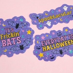 Puede incluir: Tres pegatinas hologr&aacute;ficas moradas con purpurina y estrellas. La primera pegatina dice "It's Frickin' Bats" en letras rosas y amarillas. La segunda pegatina dice "Spooktacular" en letras amarillas. La tercera pegatina dice "Everyday is Halloween" en letras rosas y amarillas.