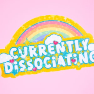 May include: Yellow sticker with a rainbow, clouds, and the text "CURRENTLY DISSOCIATING" in blue and pink letters.