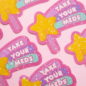May include: Five pink and purple holographic stickers with a yellow star and the text "Take Your Meds" in a rainbow font.
