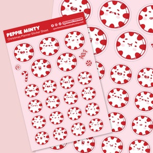 May include: A sheet of Christmas planner stickers featuring cartoon peppermint candies with smiling faces. The stickers are red and white, with a candy cane and other festive designs. The sheet is on a pink background.