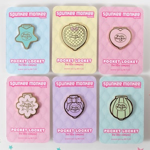 Puede incluir: Colecci&oacute;n de seis pines esmaltados sobre tarjetas pastel. Cada pin dorado tiene forma de estrella, coraz&oacute;n, flor, lazo o linterna, con el texto "Polly Pocket". Las tarjetas tienen el texto "Pocket Locket".