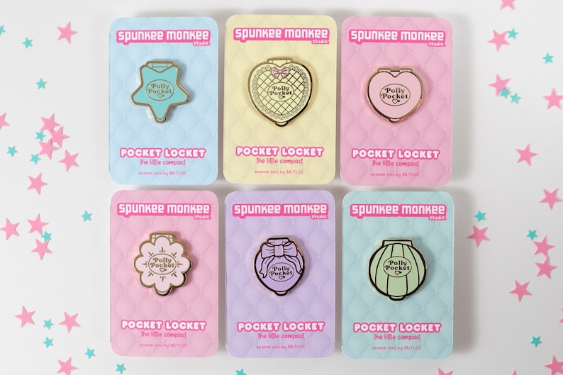 Puede incluir: Colecci&oacute;n de seis pines esmaltados sobre tarjetas pastel. Cada pin dorado tiene forma de estrella, coraz&oacute;n, flor, lazo o linterna, con el texto "Polly Pocket". Las tarjetas tienen el texto "Pocket Locket".