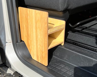 May include: A wooden storage shelf with two shelves, mounted in the back of a vehicle. The shelf is made of light wood with a natural finish.