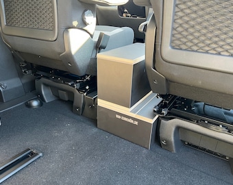 May include: A black storage box with the text "VAN-ZUBEHOER.DE" on the front, sitting in the back of a car.