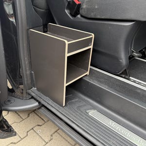 Peut inclure: Unité de rangement en bois brun foncé avec deux compartiments ouverts, conçue pour être placée à l'intérieur d'un véhicule. L'unité est rectangulaire avec un bord de couleur claire, placée près de la porte et du siège d'un véhicule.