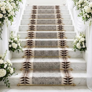 May include: Elegant marble staircase with patterned carpet runners and brass rods. The stairs are adorned with large white floral arrangements and draped white fabric, creating a luxurious and inviting atmosphere. The carpet features geometric and leaf-like designs.