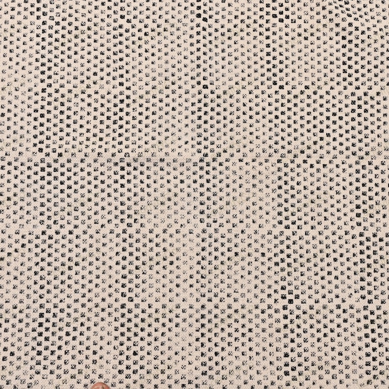 May include: A white fabric with a black checkered pattern. The fabric has a subtle texture and a slightly distressed look.