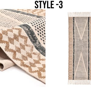 Puede incluir: Una alfombra beige y marr&oacute;n con estampado y detalles negros. La alfombra tiene flecos en los extremos y un dise&ntilde;o geom&eacute;trico.