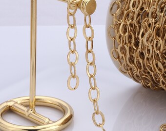 Könnte beinhalten: Eine Spule mit goldfarbener Kette und einem dekorativen Ständer. Die Kette besteht aus ovalen Gliedern.