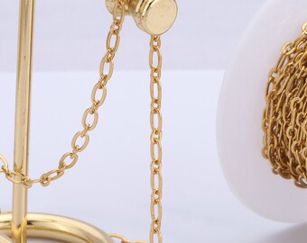 Könnte beinhalten: Eine goldene Metallkette auf einer Spule mit einem goldenen Metallständer. Die Kette hängt am Ständer und ist auf der Spule aufgewickelt.